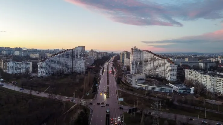 Chișinăul în amurg, văzut de sus: un bulevard cu mașini duce spre Poarta Orașului